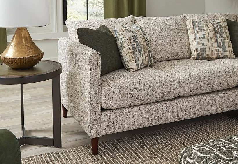 Light-colored textured sofa with green and geometric throw pillows.