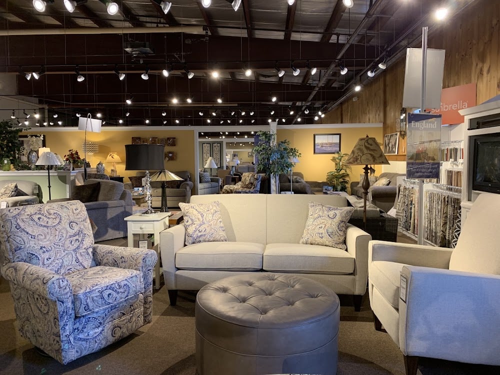 Furniture showroom with cream sofa, paisley armchair, and grey ottoman.